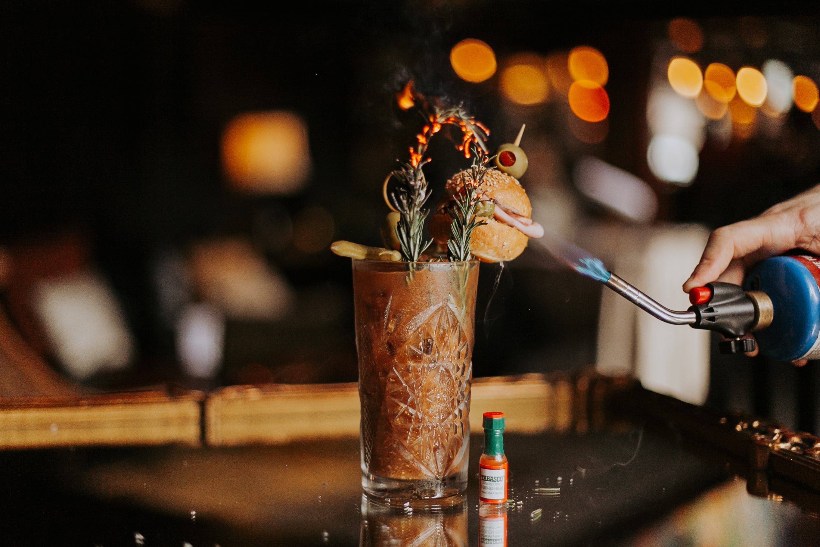a tall glass of bloody mary with garnishes and smoke