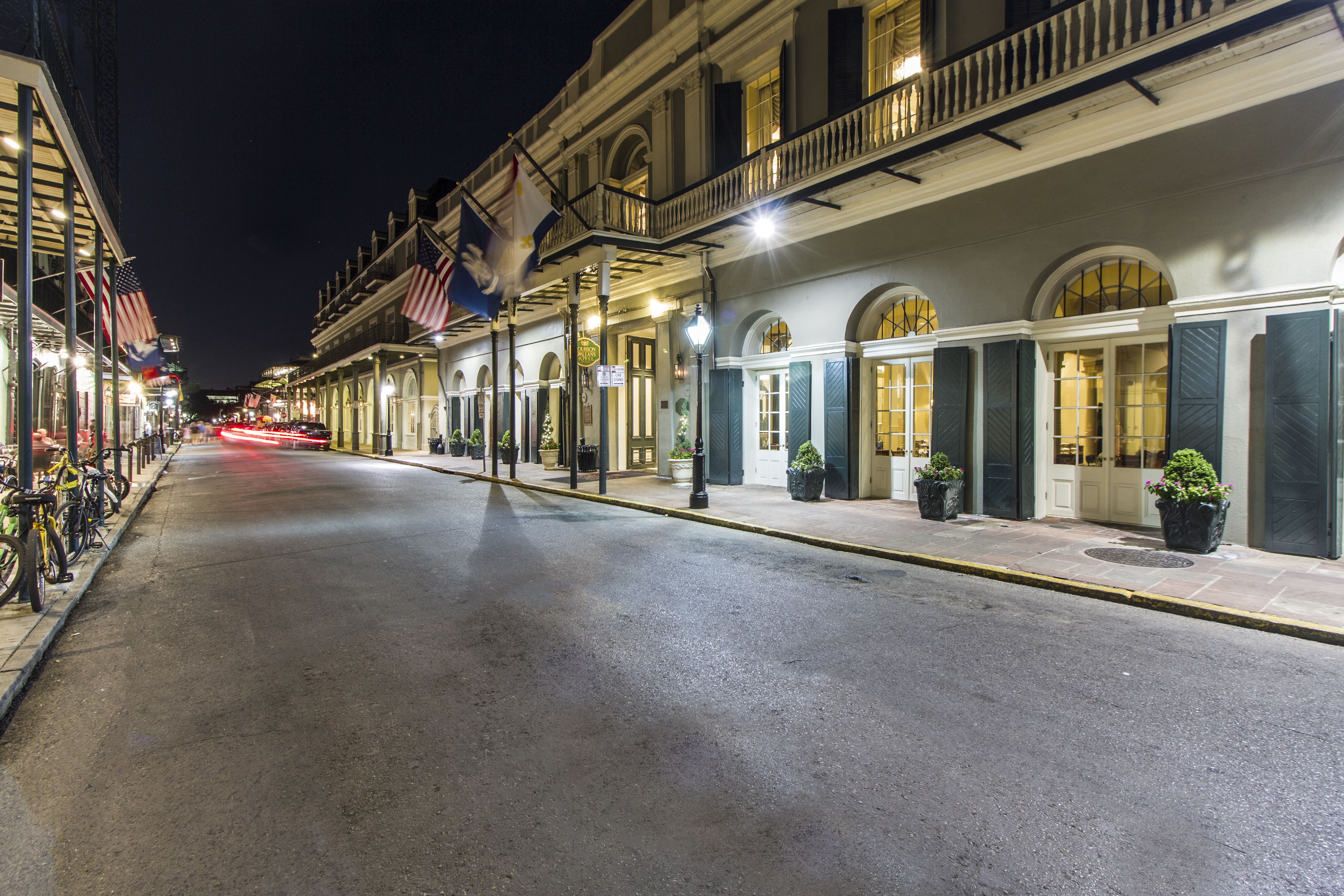 A nighttime view of a hotel exterior with flags and balcony