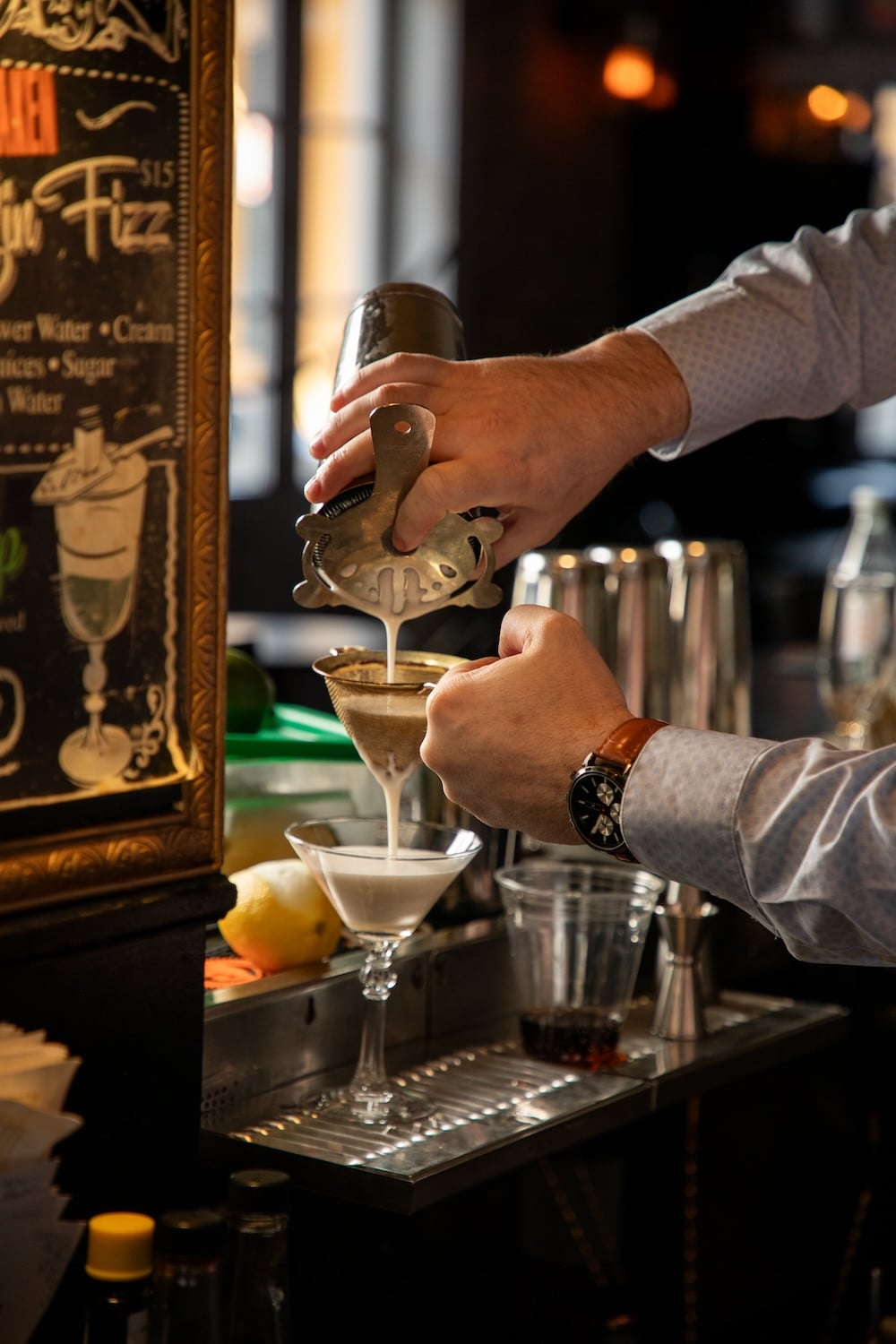 A bartender pouring a cocktail.