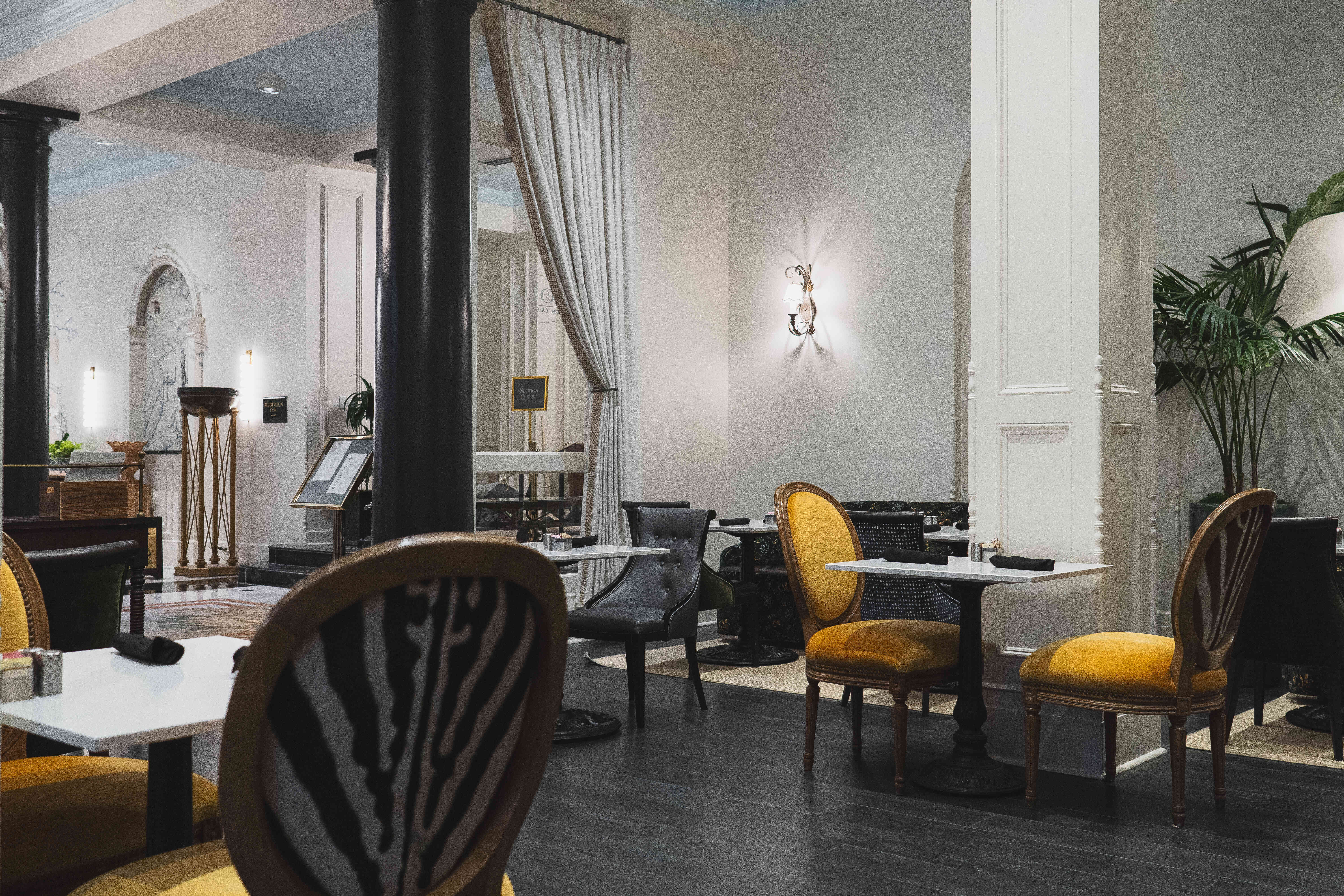 A dining area with white tables and chairs, some with yellow and black upholstery.